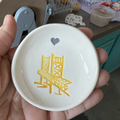 White dish with yellow design of a chair and heart held in hand