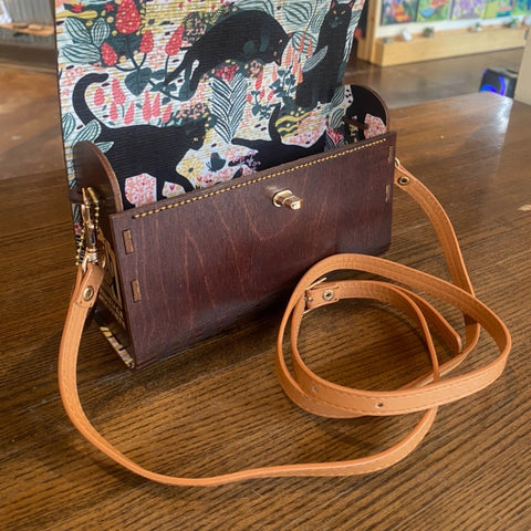 Floral-patterned handbag with a brown leather clutch on a wooden surface
