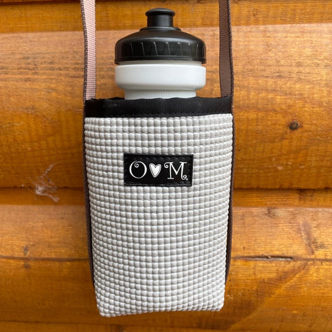 White textured bottle holder with black cap and logo on a wooden surface