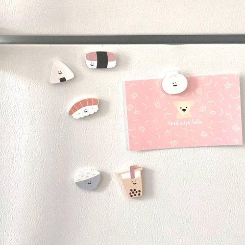 Fridge with various magnets including cartoon character and food item designs.