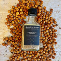 Bottle of Distilled Limoncello Pepper surrounded by roasted chickpeas on a light background