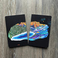 Two black cards with colorful mountain designs on a wooden surface