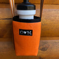 Orange water bottle holder with black cap and logo on a wooden background