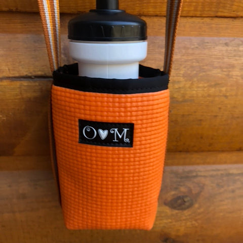 Orange water bottle holder with black cap and logo on a wooden background