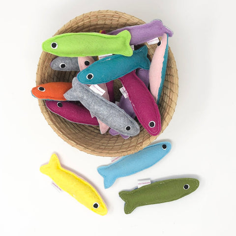 Colorful fish-shaped toys in a woven basket on a white background