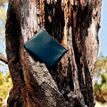 Green leather wallet attached to a tree trunk with a natural background