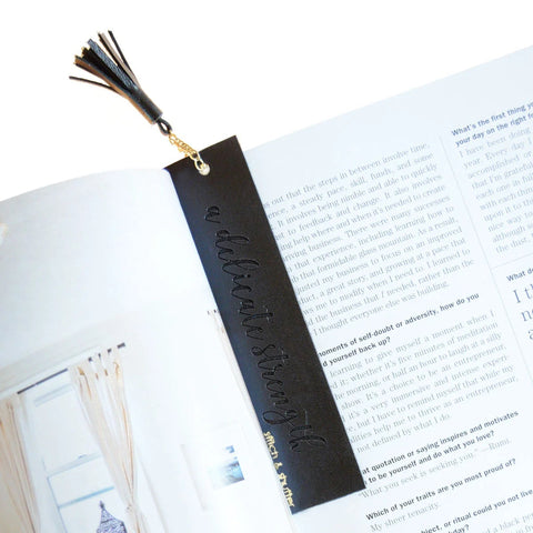 Black leather bookmark with tassel on an open book