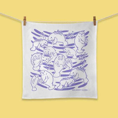 White towel with purple manatee design hanging on a clothesline against a yellow background