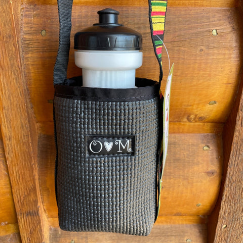 Water bottle with black cap and gray holder on a wooden surface
