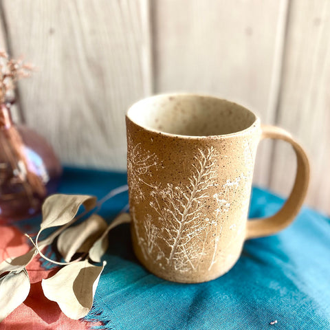 Ceramic mug with tree design on a blue surface with a blurred background