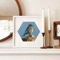Framed artwork of a bird on a shelf with candles and a mirror.