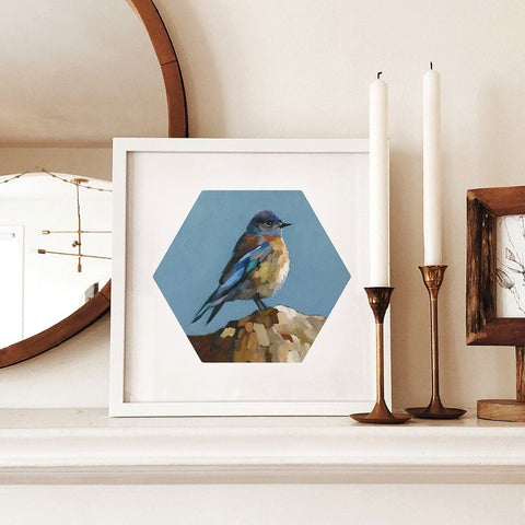Framed artwork of a bird on a shelf with candles and a mirror.