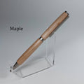 A wooden ballpoint pen with a natural maple wood finish and silver metal accents, displayed on a clear acrylic stand against a neutral gray background. The word 'Maple' is printed in black text on the left side.