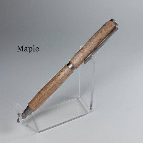 A wooden ballpoint pen with a natural maple wood finish and silver metal accents, displayed on a clear acrylic stand against a neutral gray background. The word 'Maple' is printed in black text on the left side.