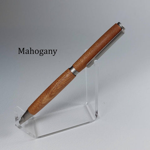 A wooden pen with a warm mahogany brown finish and silver metal accents, displayed on a clear acrylic stand against a neutral gray background. The word 'Mahogany' is printed in black text on the left side.