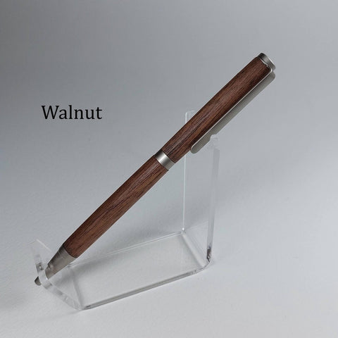 A wooden pen with a dark walnut finish and silver metal accents, displayed on a clear acrylic stand against a neutral gray background. The word 'Walnut' is printed in black text on the left side.