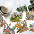 Set of animal stickers by Julie Townsend Studio on a textured surface with a cup and leaves.