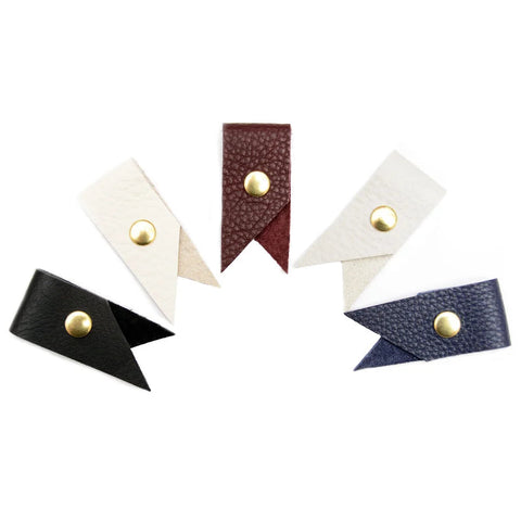 Set of five leather tags with gold studs on a white background