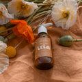Bottle of 'Lorie' on a textured surface with flowers around it