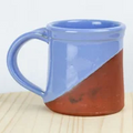 Ceramic mug with blue top and brown bottom on a wooden surface