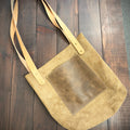 Beige handbag with a square patch on a wooden surface