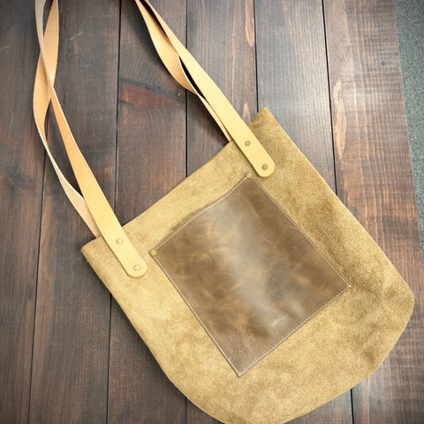 Beige handbag with a square patch on a wooden surface