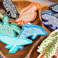 Colorful dolphin-shaped coasters on a wooden tray