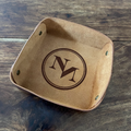 Brown leather tray with engraved logo on a wooden surface