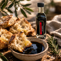 Balsamic vinegar bottle with bread and balsamic glaze on a wooden board