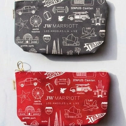 Two pouches, one gray and one red, with JW Marriott branding and travel-themed illustrations on a white background.