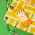 Hand sanitizer wipes on a yellow and white striped bag against a green background