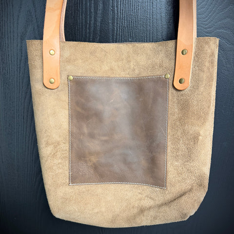 Beige tote bag with brown leather accents on a dark blue background