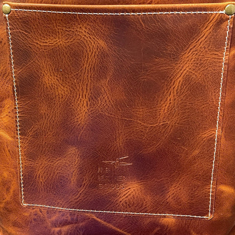 Brown leather tote bag with visible stitching on a gray surface