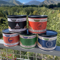 Five cans of Belmont Peanuts stacked on a metal railing with a scenic background