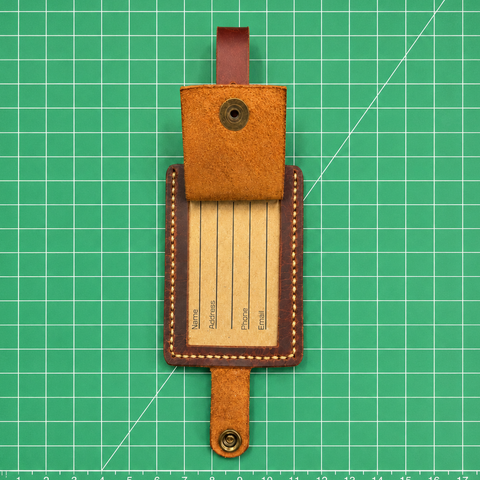 Brown leather luggage tag on a green grid background