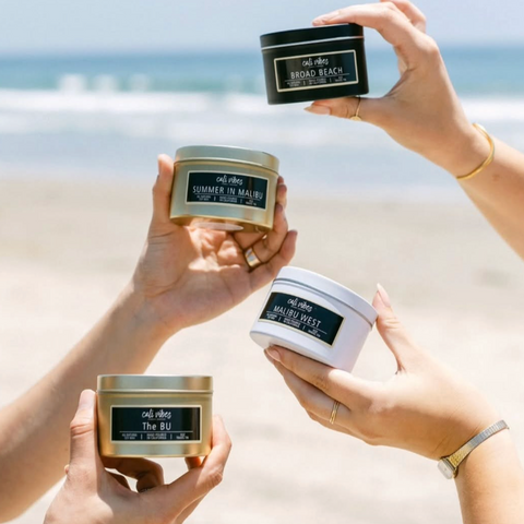 Hands holding Calm Vibes candles with a beach background