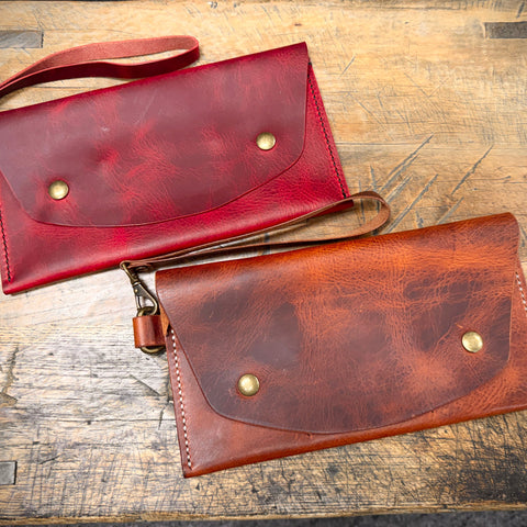 Two leather bags, one red and one brown, on a wooden surface.