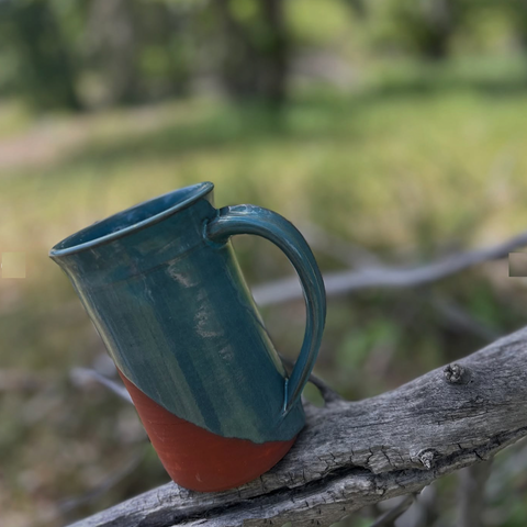 Blue ceramic mug on a branch with a blurred natural background